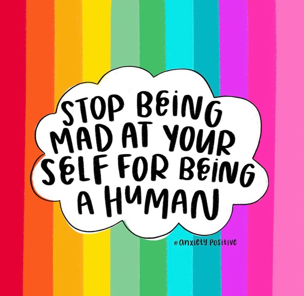 Vertical stripes run left to right in this order: deep red, orange, amber, yellow, pale yellow, light green, mid-green, teal, aqua, bright fuchsia, hot pink, and pale pink. No purple is present. In the centre, a white cloud-shaped bubble contains bold, hand-lettered text on five lines: “STOP BEING / MAD AT YOUR / SELF FOR BEING / A HUMAN”. The artist credit “@anxiety.positive” appears near the lower right of the cloud. Picture by @anxiety.positive.