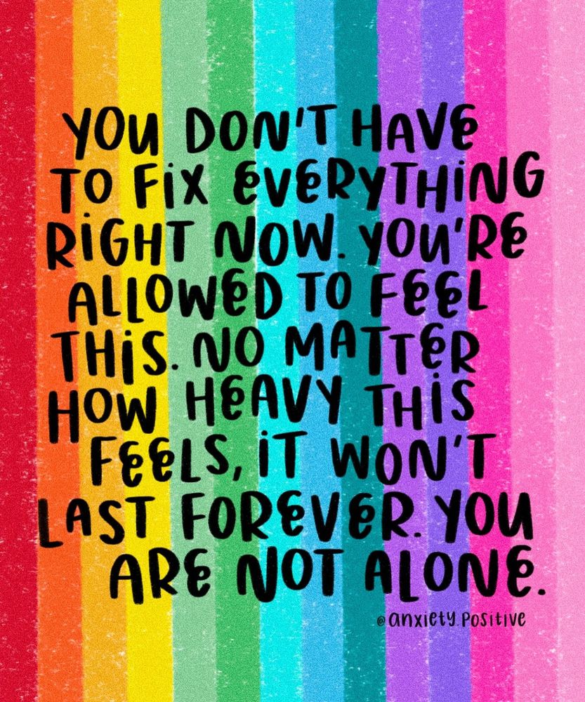 A rainbow-striped background features the words in bold black hand-drawn lettering: “You don’t have to fix everything right now. You’re allowed to feel this. No matter how heavy this feels, it won’t last forever. You are not alone.” – @anxiety.positive. The colours fade softly from red through orange, yellow, green, blue, indigo, and pink, giving a comforting and supportive visual tone.