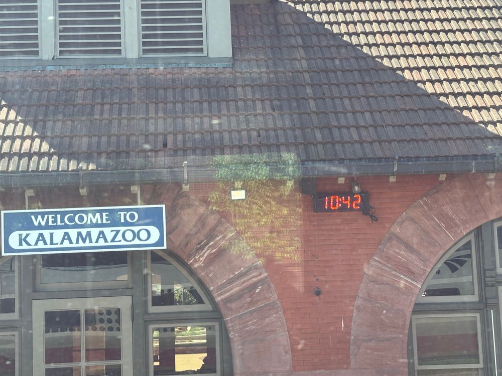 Photo of Kalamazoo railway station building showing red brick, a welcome to Kalamazoo sign and a digital clock
