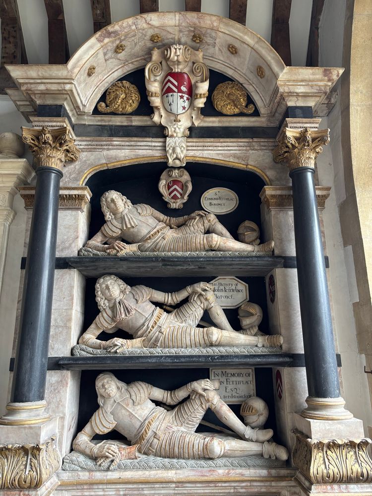 Three tiered funerary monument in marble showing reclining figures in Stuart era armour, commemorating members of the Fettiplace family, St Mary’s Church, Swinbrook, UK