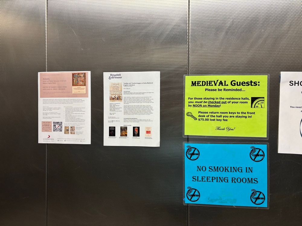 Photo of assorted fliers in a lift at university of western Michigan, for books and announcements for conference attendees