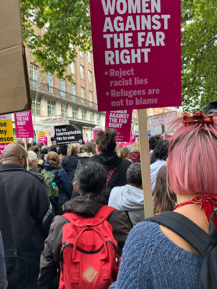 Photograph of protest marchers holding banners with slogans including Women against the far right. 