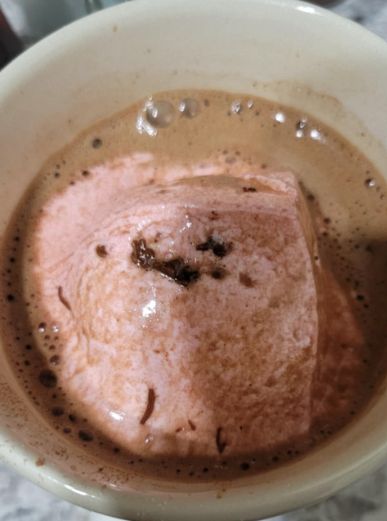 Hot cocoa in a mug topped with a fancy strawberry marshmallow