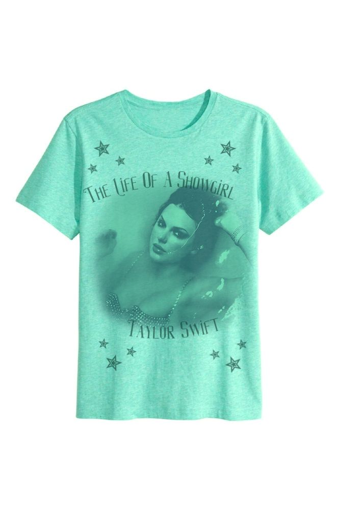 A light green tee shirt with a picture of Taylor Swift's The Life Of A Showgirl album cover and the text "The Life Of A Showgirl Taylor Swift" printed on it