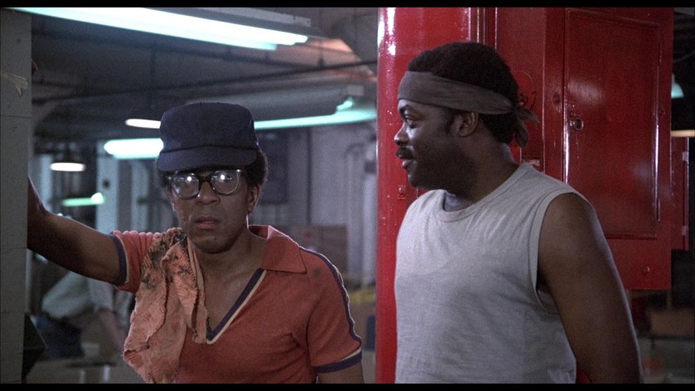 Still from the 1978 movie Blue Collar: Richard Pryor and Yaphet Kotto standing in a automobile assembly shop.