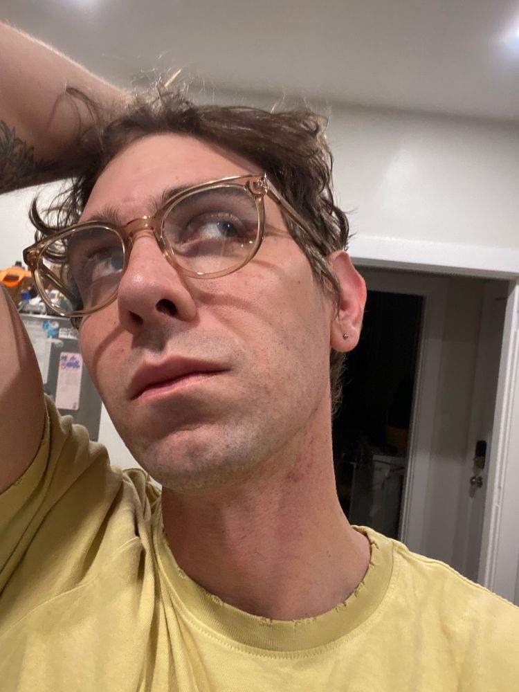 selfie of me wearing new glasses that are a little big for my face with clearish nutmeg frames. sorry I know this alt text is bad I’m so fucking fried rn 