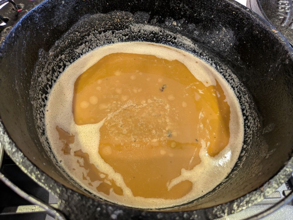 closeup of a peanut butter colored roux in a large Dutch oven.