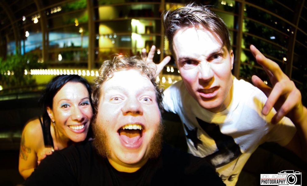 Drunk man in chops posing with Matt & Kim