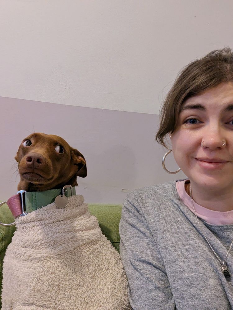 Grace smiling sitting next to a stylish dog giving her side-eye
