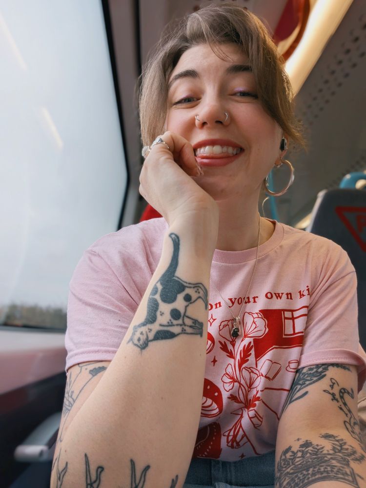 Grace posing on a train in a pink 🩷 and red t-shirt