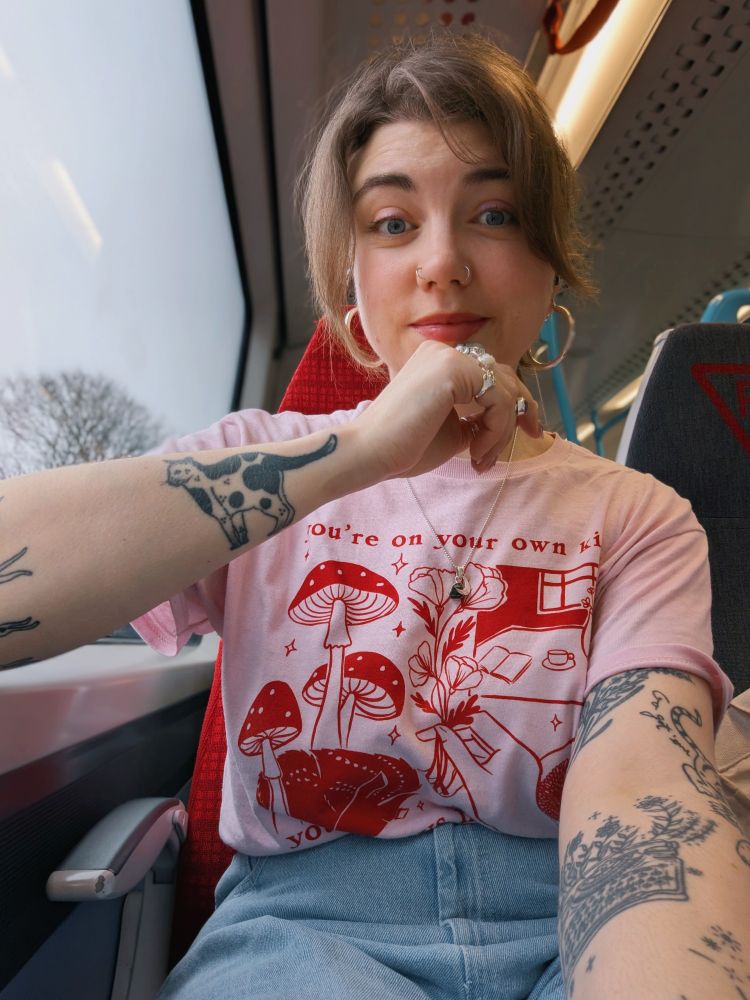 Grace posing on a train in a pink 🩷 and red t-shirt 