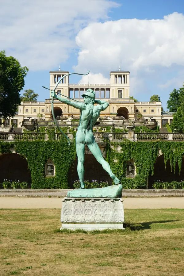 Brightly lit photo from behind the Apollo statue in the garden of Orangery Palace, Sassouci Park in Potsdam, Germany.