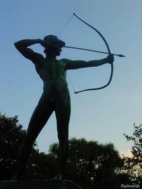 A shadowy photograph of the nude Apollo archer statue in Sanssouci Park in Potsdam, Germany.