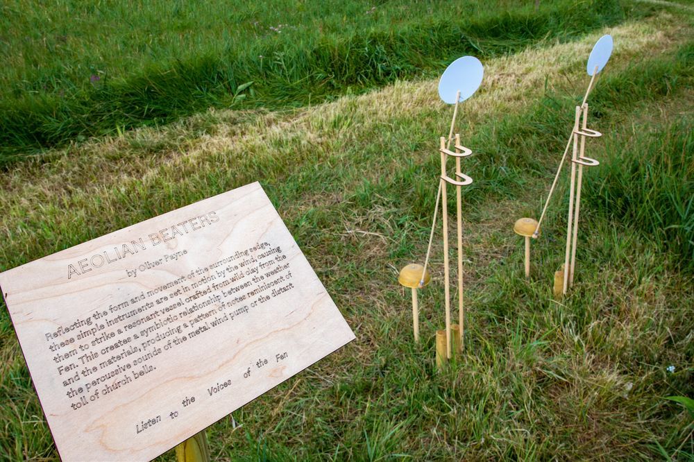 a sign reads Aeolian Beaters next to two sound scupltures on the grass