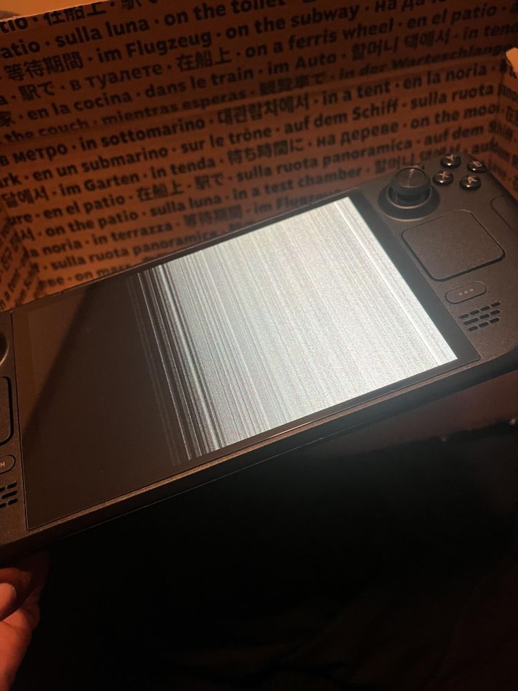(Pas ma photo) d'un Steam Deck OLED noir affichant des lignes blanches verticales sur une partie de l'écran au démarrage.