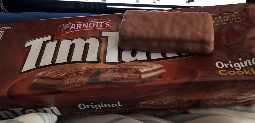 Brown Arnott’s Tim Tams cookie package with a rectangular chocolate cookie on top. 