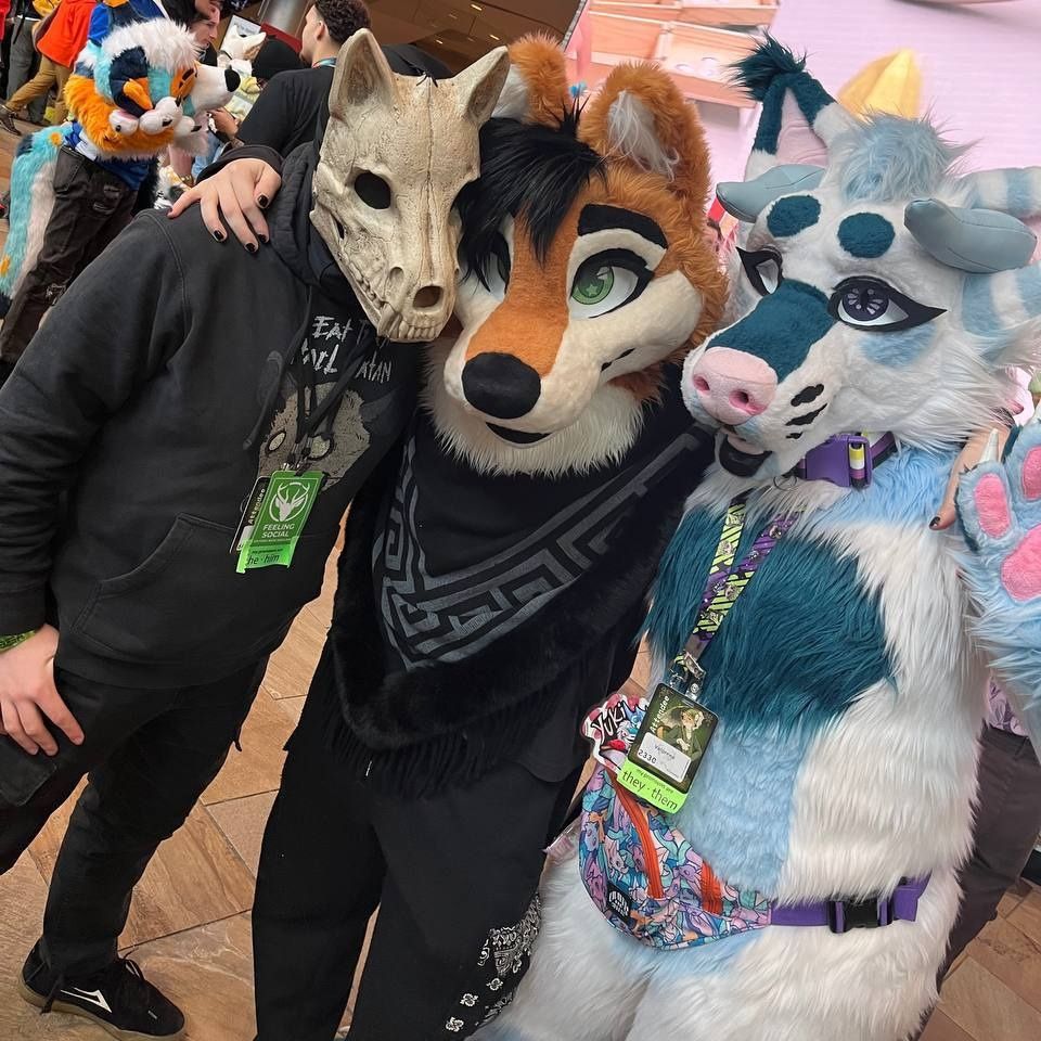 A skulldog suiter (left), shiba inu suiter named Sticky (middle), and me suiting as Yuki, a white and blue Hellhound. (right) We're all shoulder-to-shoulder, and I'm holding a paw up in a waving pose.