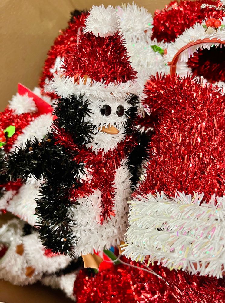 Another cheap tinsel penguin Christmas decoration, beside other cheap tinsel decorations like a Santa hat.
