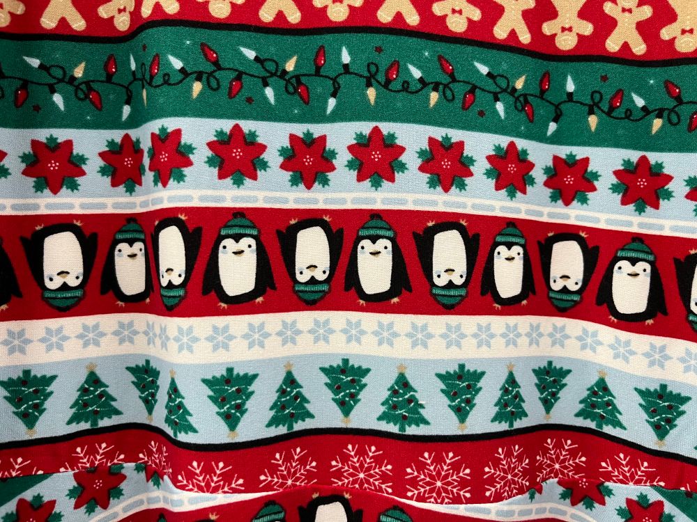 A Christmas jumper / sweater featuring penguins along with Yule trees, snowflakes, festive lights, etc.