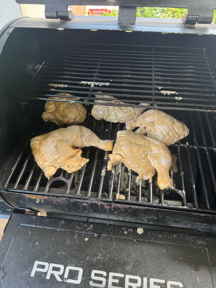 Five thigh/leg combo slathered in marinade sitting on the smoker. 