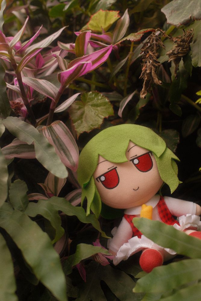 Yuuka blending in among some leaves and purple flowers.