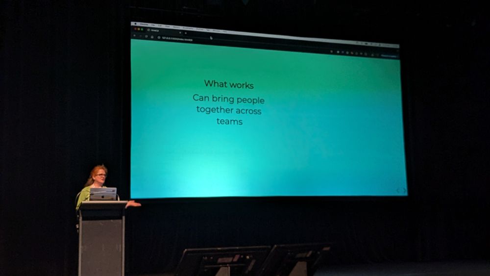 Leah in front of slides that reads "what works can bring people together across teams"
