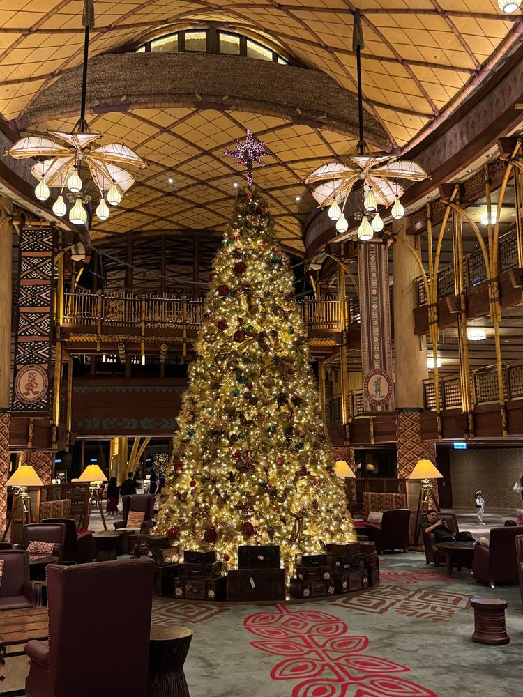 Christmas tree covered in warm yellow lights in a large hotel lobby with an African/adventure theme