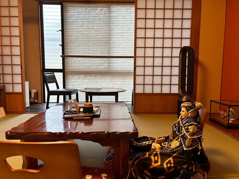 A replica puppet of Wan Jun Po from Thunderbolt Fantasy seated at a traditional Japanese inn