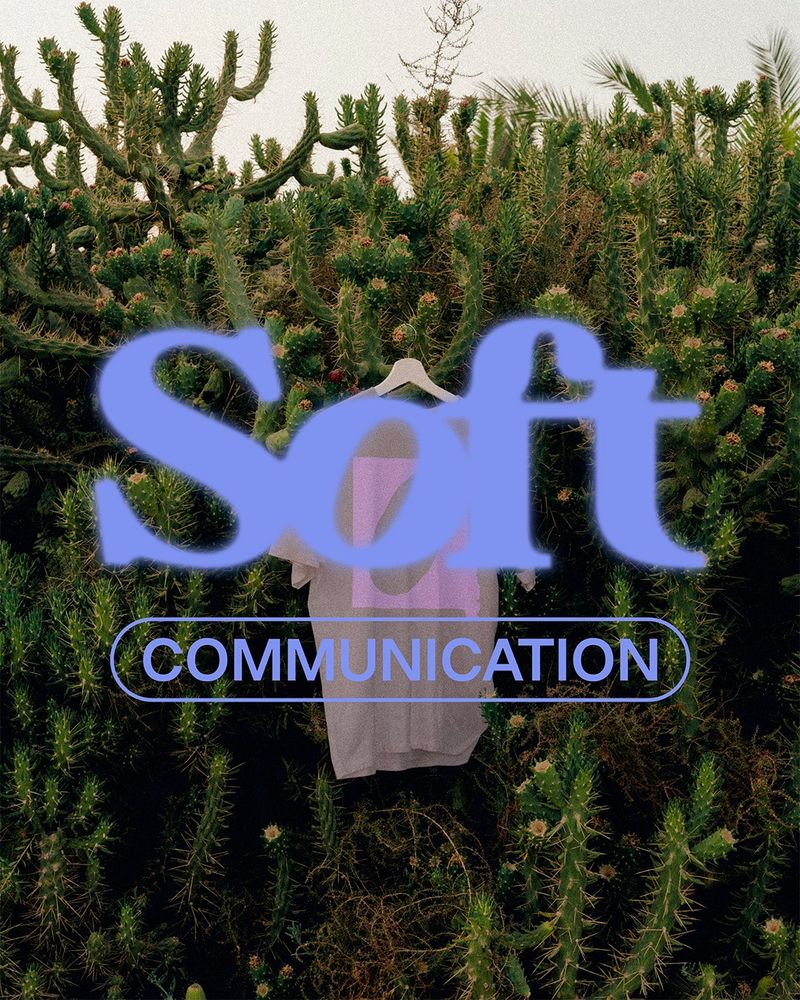 Das hellblaue Logo Soft communication liegt auf einem Bild einer grünen Kakteen-Hecke an der ein beiges T-Shirt mit dem rosa Bildzeichen hängt.
