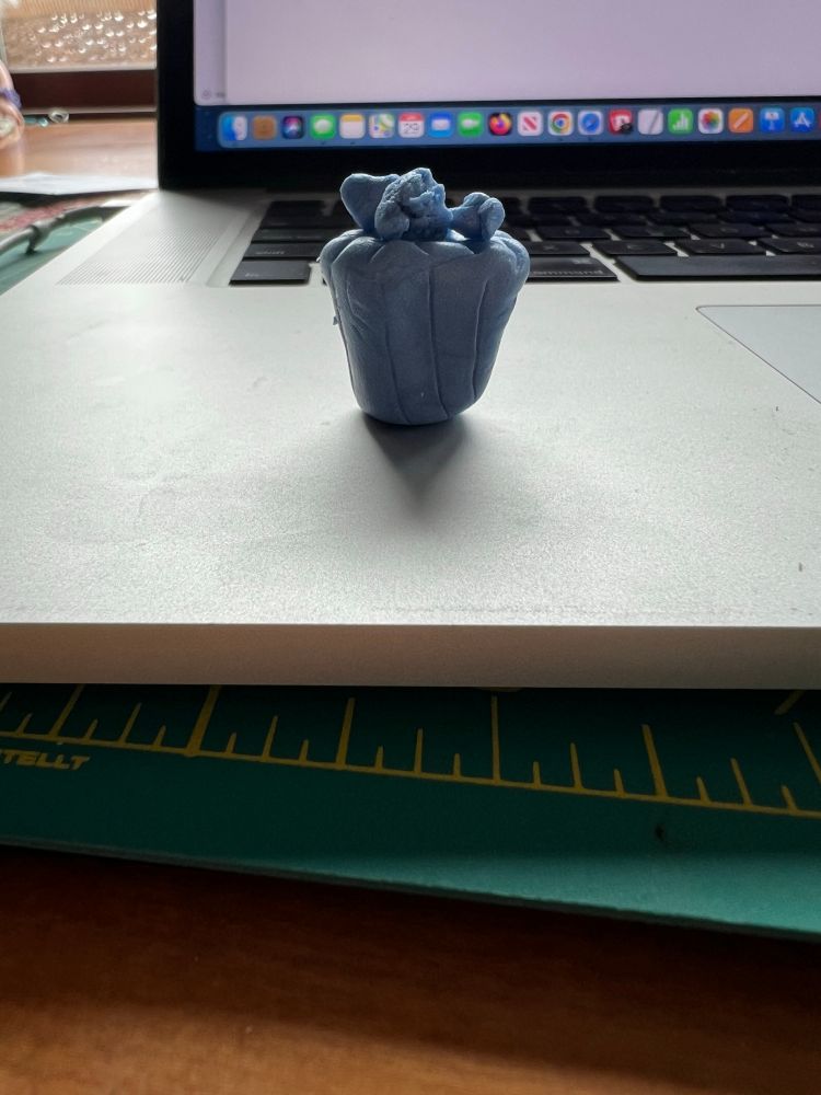 a simplified bag of popcorn sculpted in light blue clay, sitting on a laptop 