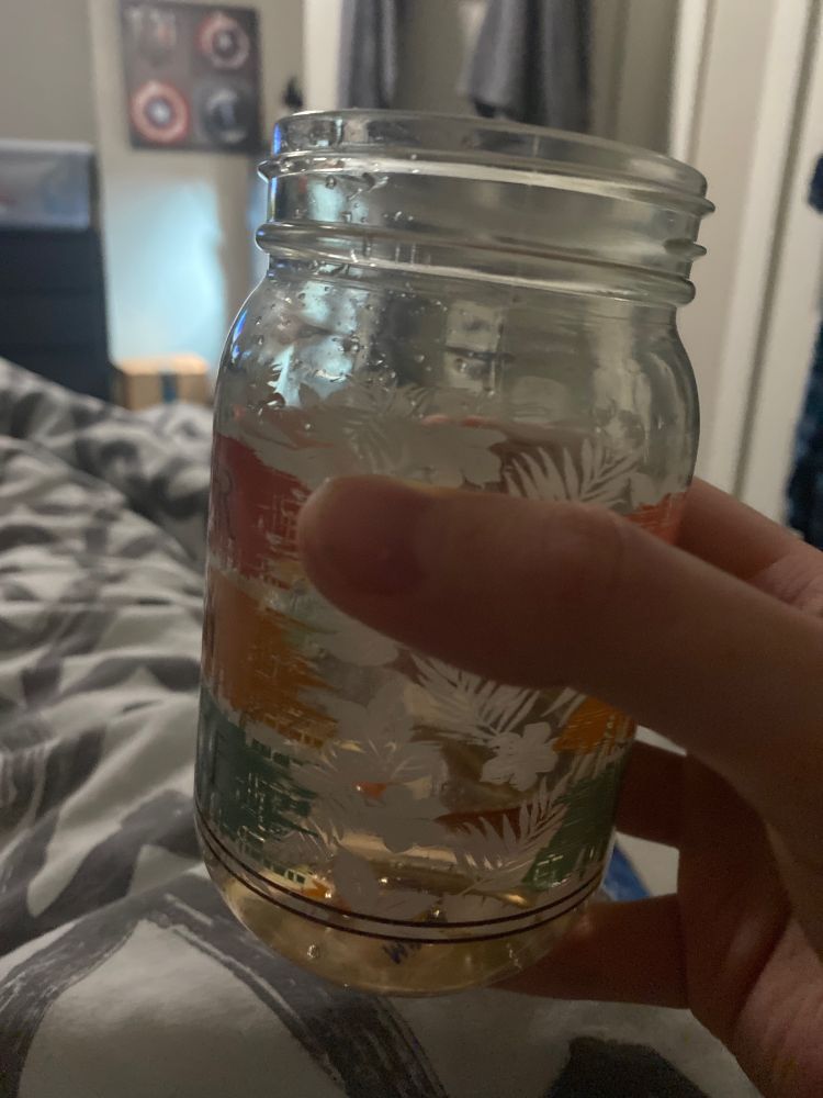 A hand holding a glass with tropical designs printed on it.