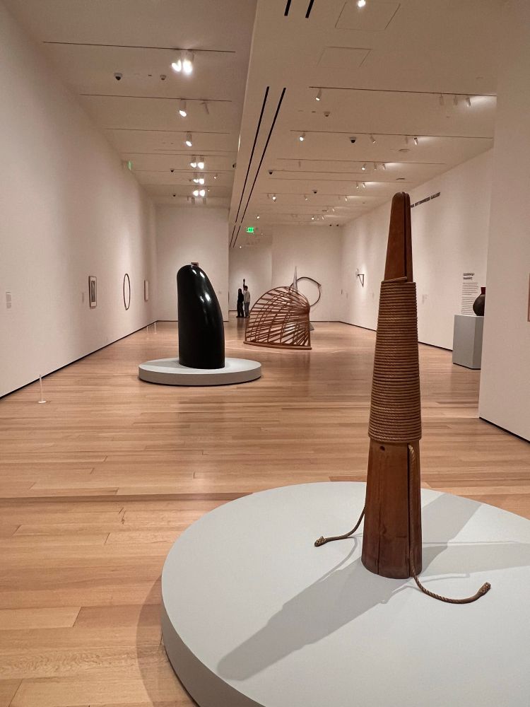 Several sculptures by the artist Martin Puryear stand in an exhibition space at the Museum of Fine Art in Boston, MA. The sculptures are made of various materials, mostly wood.