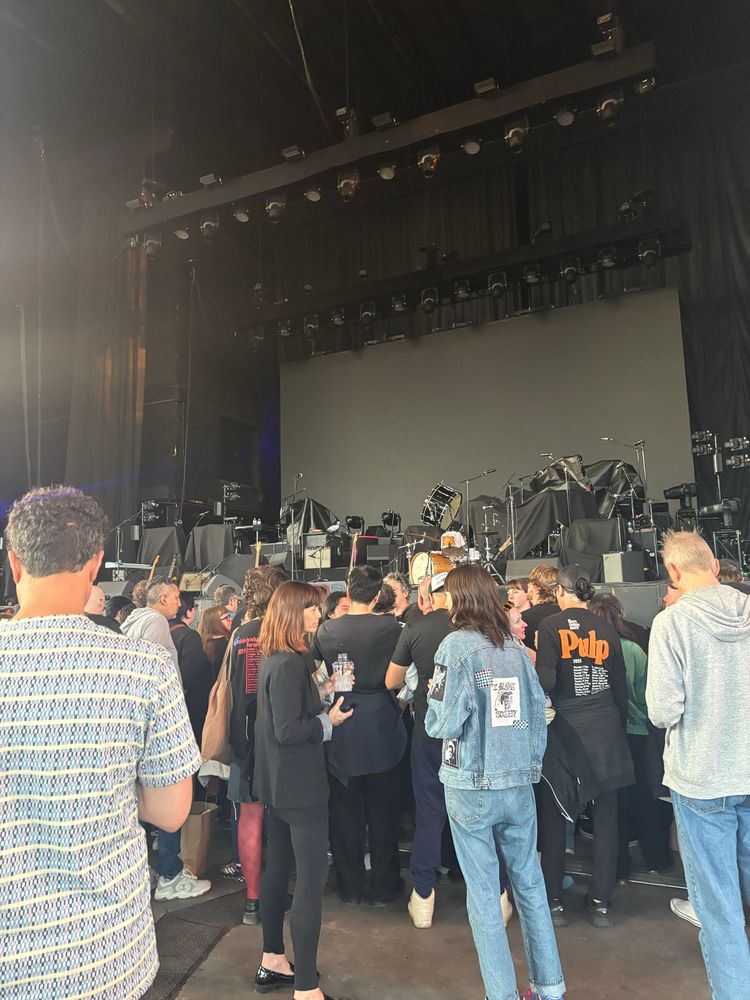 A crowd of people stand in front of a stage.