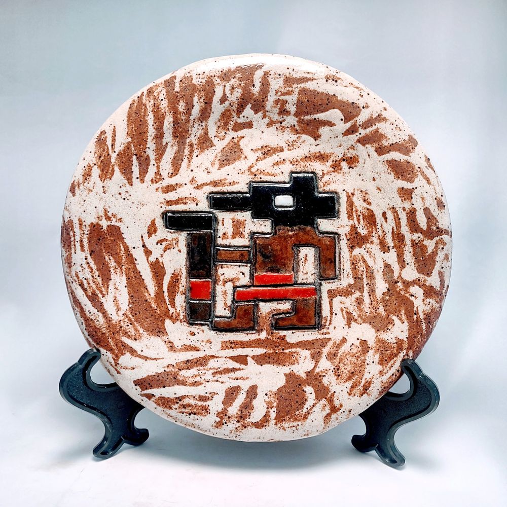 handmade ceramic plate carved with a pixelated image of the Egyptian god Anubis from Riddle of the Sphinx, 1982 game for the Atari 2600.