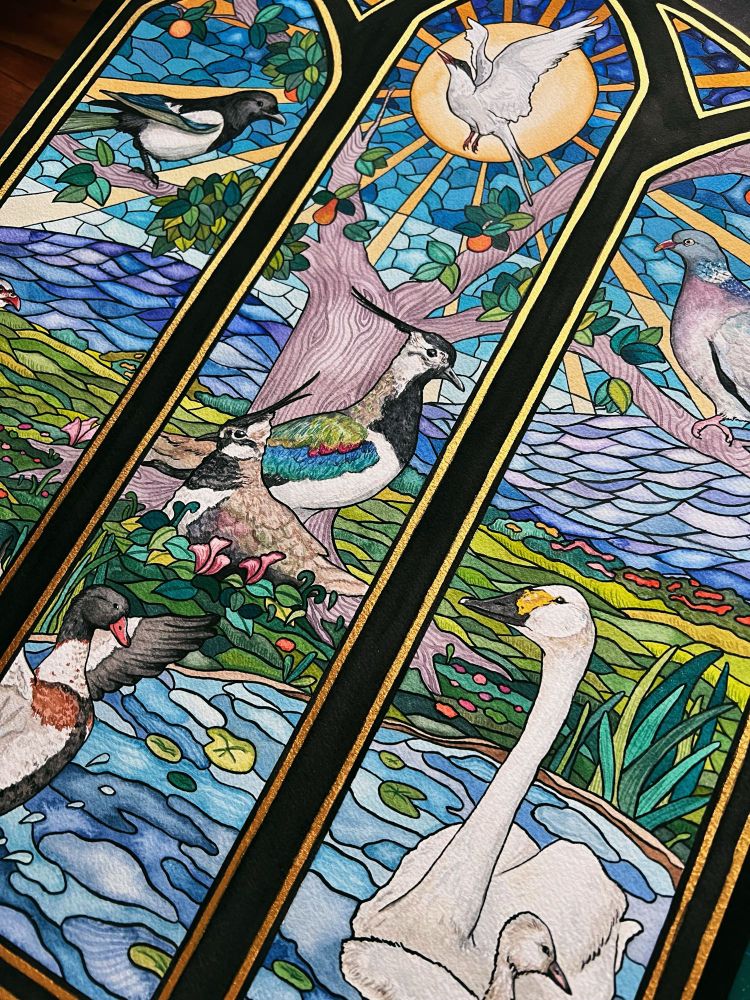Picture of Julie’s large watercolor piece “St. Patrick’s Green” inspired by stained glass and featuring seven bird species found in Ireland. 

The painting is a landscape featuring a duck and swan in a pond, a pheasant and pair of lapwings in the field, a magpie and woodpigeon in a tree, and arctic tern flying in the sky. In the background are mountains and a bright sun. 