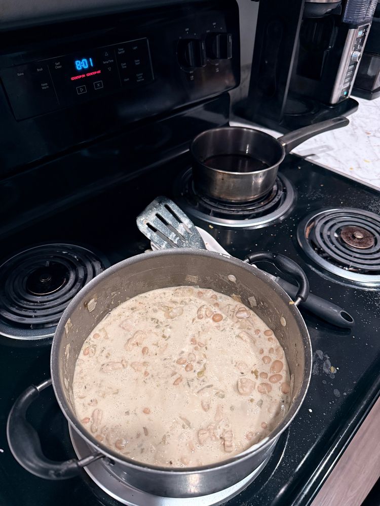 Pot of chili and smaller pot of brown syrup on a (messy) stove 