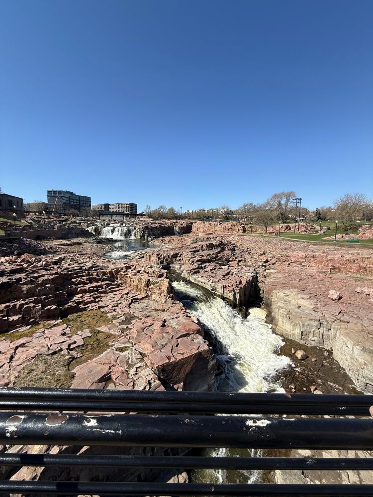 Rocky waterfall with a cityscape in the background. 