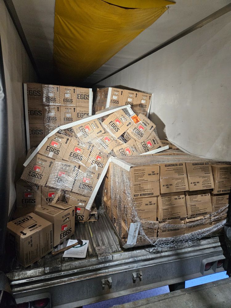 Picture of the back of a semi trailer with 2 pallets of eggs that have tipped over.