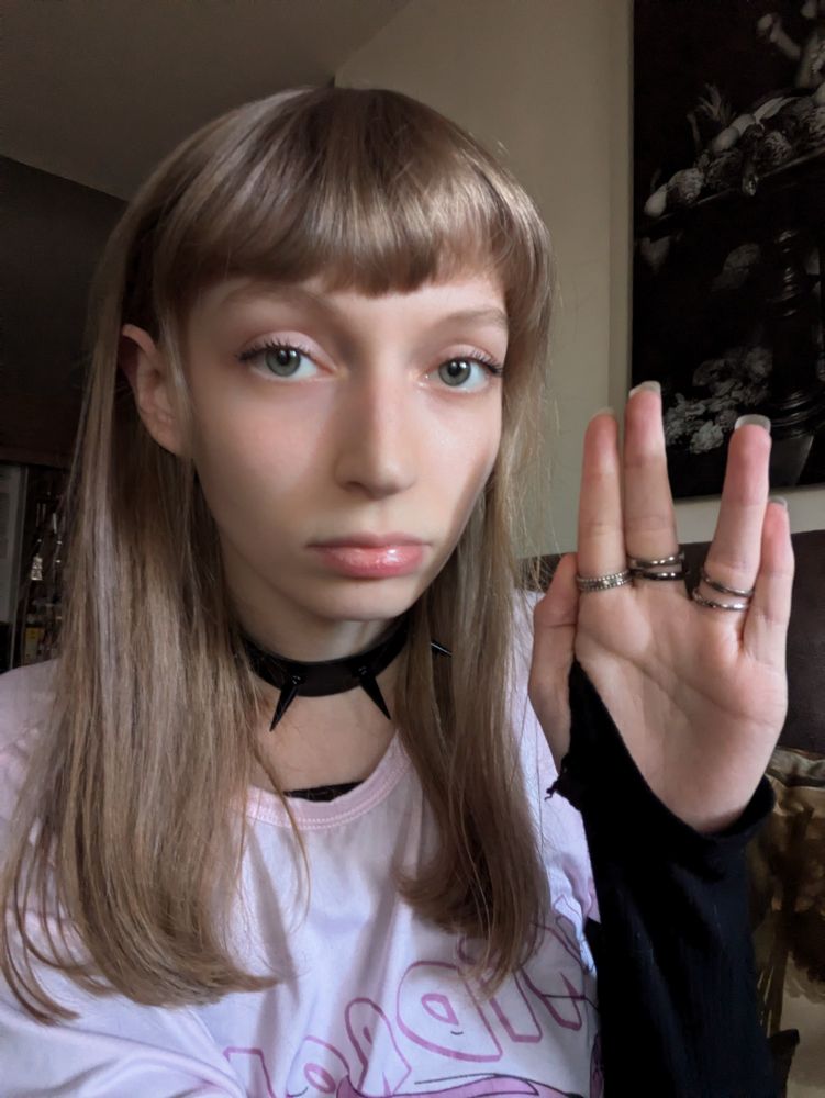 A girl holding her hand up in the Spock hand pose.