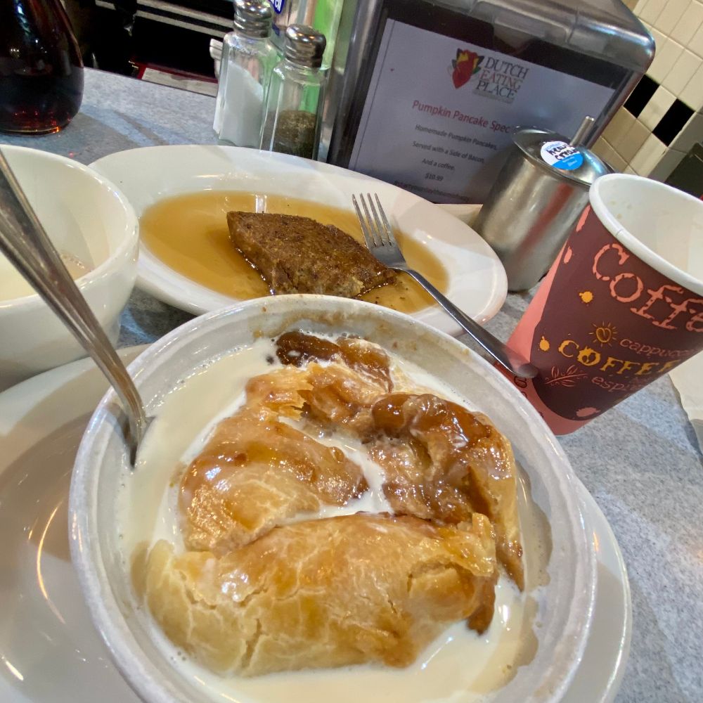 Apple dumpling in a bowl of warm heavy cream at the counter of the Dutch Eating Place in Reading Terminal, Philadelphia.