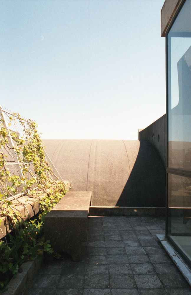 View of the roof of Le Corbusier's Appartement in the Molitor building, Paris. The view shows a small terrasse with a concrete bank and a glass façade and on the backround, the arched roof, half in shadow and half in sunlight.
This work is licensed under CC BY-NC-SA 4.0