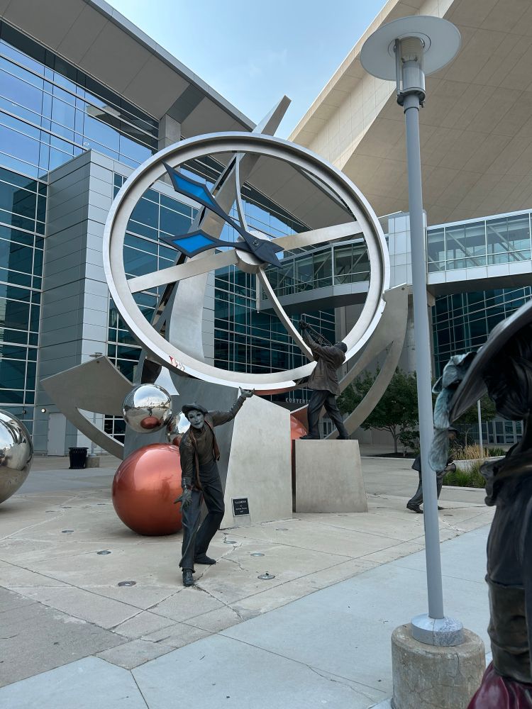 Sculptures, one is a hat tipping mime