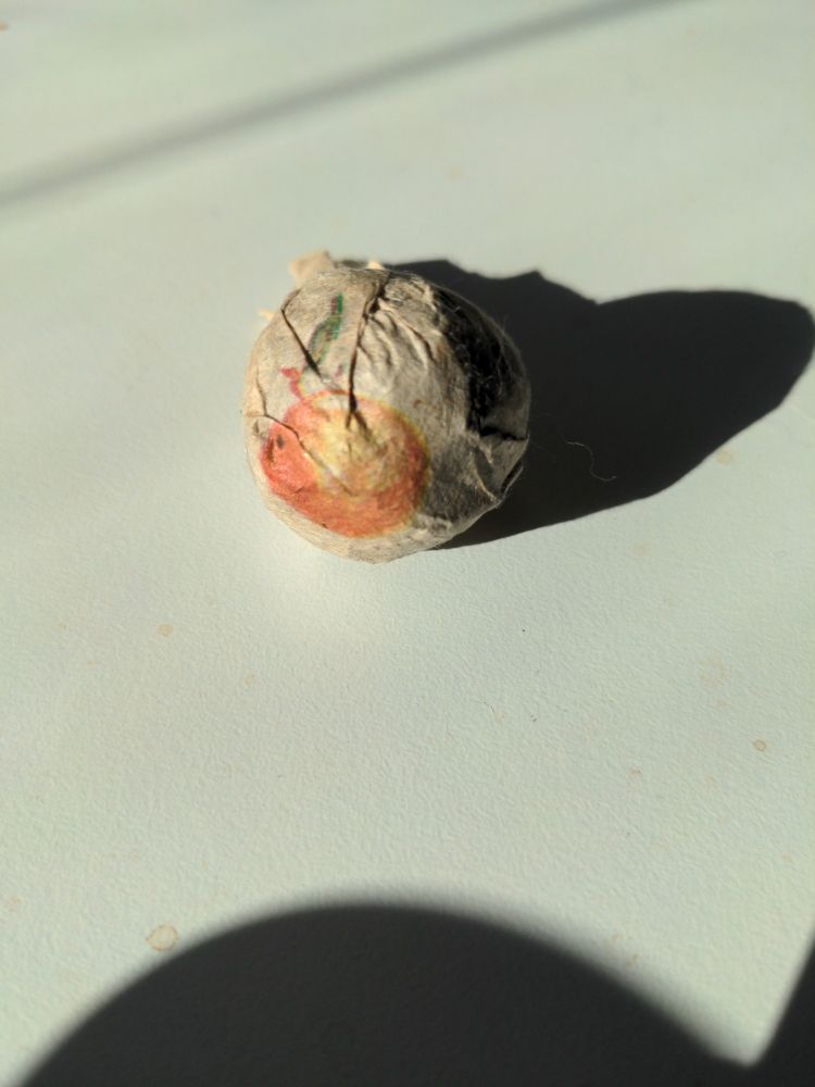 small tea ball in a paper wrapper with an orange on it
