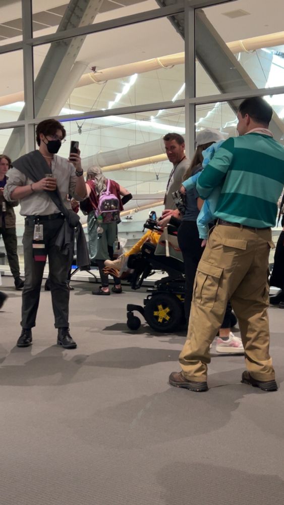 Palamedes Sextus holding an iced coffee, taking a photo of a father dressed as Steve Blues Clues and his infant daughter dressed as Blue