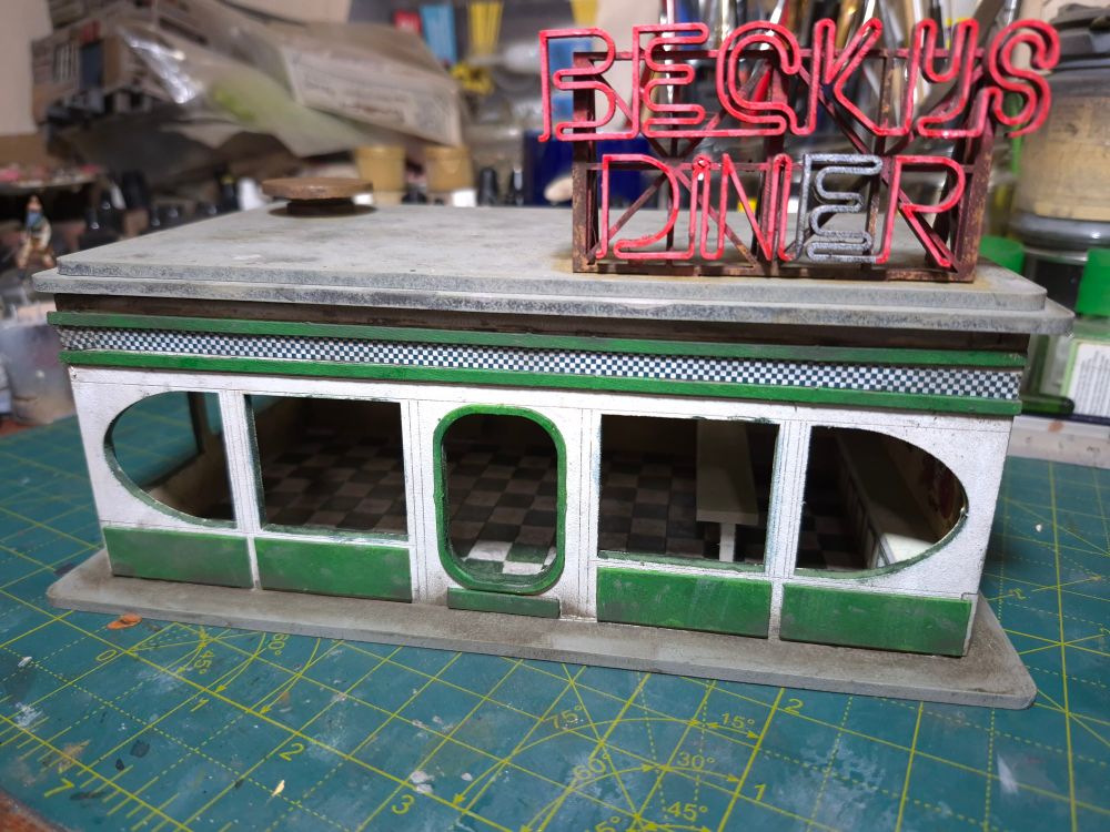 28mm scale miniature diner, painted white and green with a broken red neon sign