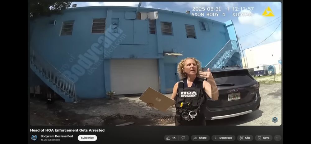 A woman wearing a vest labeled “HOA Enforcement” stands in front of a black SUV and a blue building, holding a clipboard while speaking.