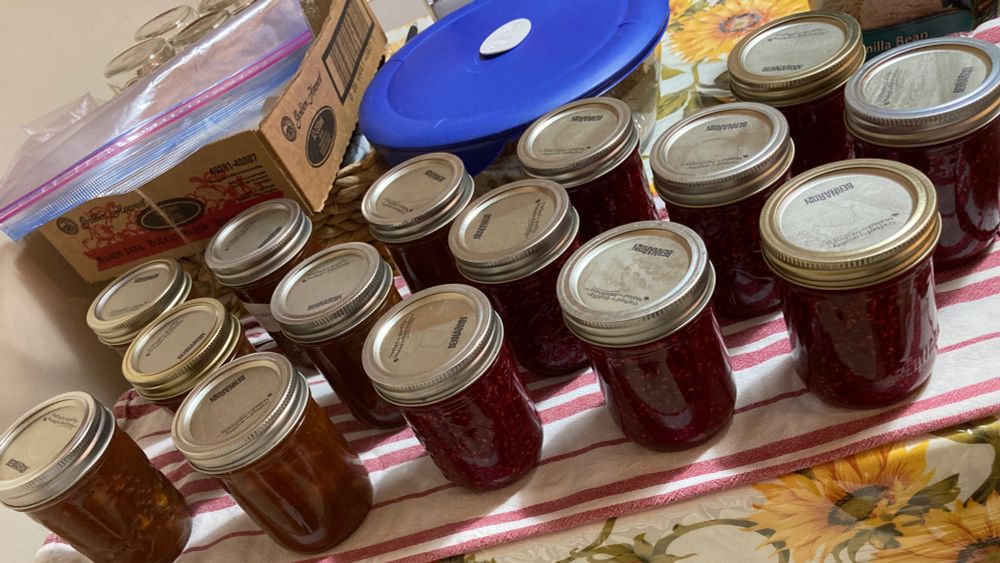 Table with home canning cooling on it.  Rhubarb-Orange Marmalade and Raspberry Jam. 