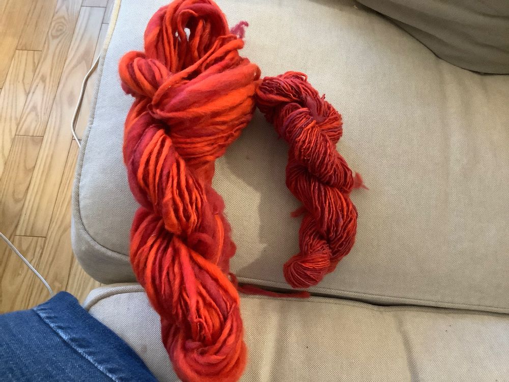 2 skeins of Red yarn. Singles. Hand spun. The first is thick and thin singles. The second is energized fine singles. 