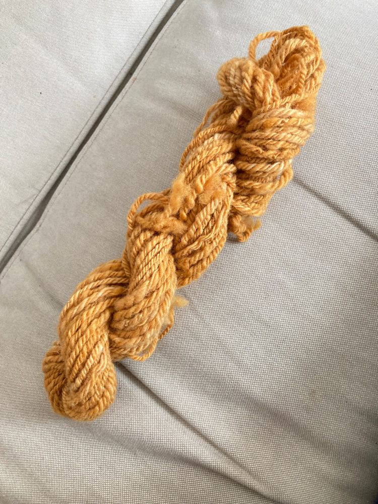 Skein of caramel coloured hand spun wool yarn. Chain plied.  Thick.