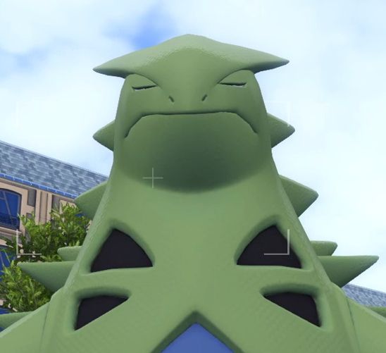 A gameplay screenshot of Pokemon Legends: Z-A. My Tyranitar is facing forward with his eyes mid-blink. Looks like he's trying not to laugh.